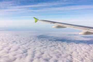 View from the airplane window at a beautiful blue sunrise and the airplane wing above the clouds.