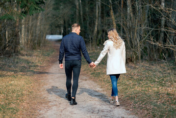 Obraz premium Beautiful loving couple going for a walk in a forest in the spring,autumn outdoors sunny day.Rear view.