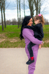 Obraz premium Beautiful mother and daughter play hugs in a summer park nature in profile looking at each other.