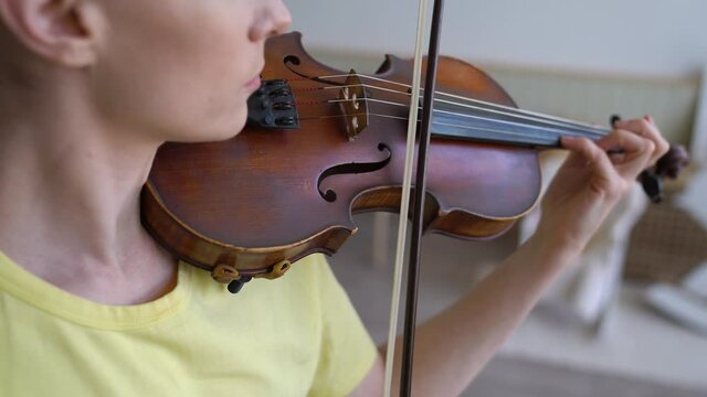 Extreme close up Over-the-shoulder Shot  Of Beautiful Young Woman Skilfully Plays The Violin. High-key Lighting Shot