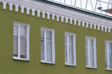  Elements of the architectural decor of the building. A fragment of the facade of a restored old house with color walls and white window frames.