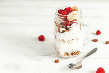 Oatmeal granola with yogurt, berries and nuts in a jar. A healthy, home-cooked vegetarian breakfast. Place for text