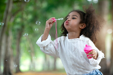 Little girl fun with soap bubbles in the park