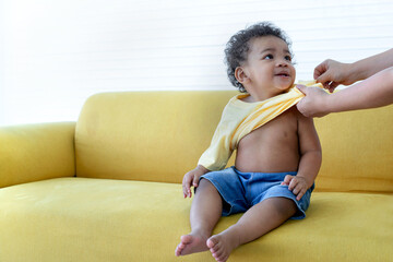Little boy happy while getting dressed by his mom on couch, smile and looking at mom
