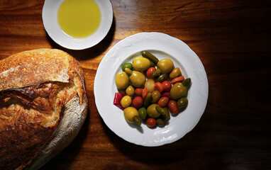 Fototapeta na wymiar Variety of spanish olives, olive oil and a bread on a wood background