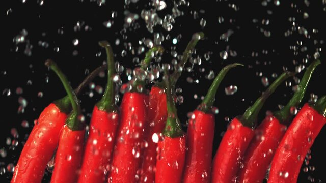 Super slow motion on red hot chili pepper drops water. On a black background.Filmed on a high-speed camera at 1000 fps. High quality FullHD footage