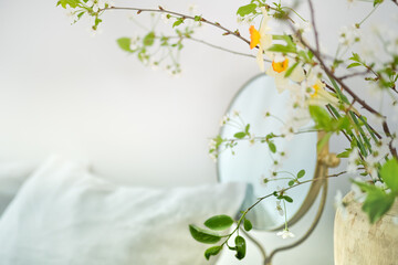 Abstract background of blurred bedroom with branch of fresh flowers on foreground