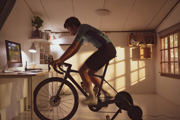 Asian man cyclist. She is exercising in the house.By cycling on the trainer and play online bike games..