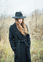 Portrait of young attractive woman in black coat and hat.