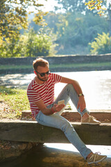 Young adult man using modern smartphone in the park.