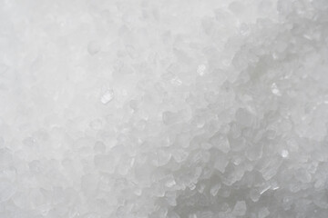 Textured background, top view of a pile of grains of white sea salt.