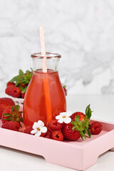 Red strawberry fruit lemonade in jar surrounded by berries