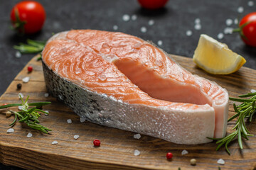 Raw salmon steak pepper salt dill lemon and rosemary on wooden table.