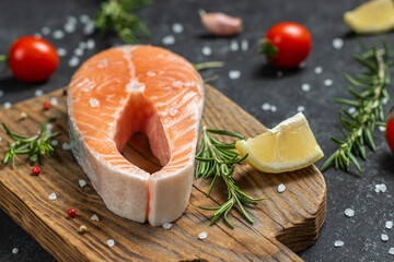 Fresh raw salmon fish steak with spices on dark wooden background.