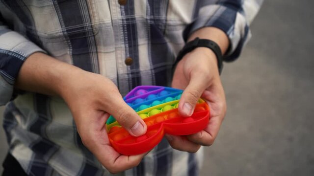 man plays pop it toy simple dimple standing on the street.