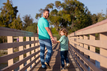 Fototapeta na wymiar Father with son walking on wooded bridge outdoor.