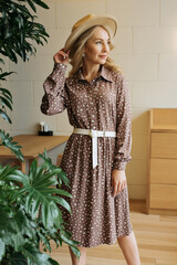 Luxurious young slim girl with long hair in a long dress with a floral print and a straw hat....