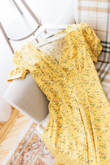 A yellow floral dress lies on the sofa