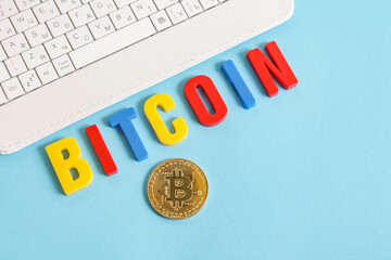 Cryptocurrency for kids. White keyboard, Bitcoin word from colorful letters on blue background