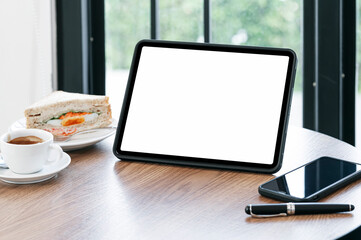 Blank screen tablet, smartphone and coffee cup on wooden table in cafe.