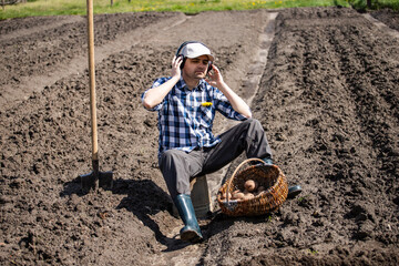 person planting potatoes in the field and listens to music