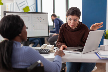 African handicapped invalid entrepreneur in wheelchair working with project manager calculating...