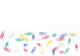 Study concept background. Colorful office stationery: drawing pins and clips on white background with copy space 
