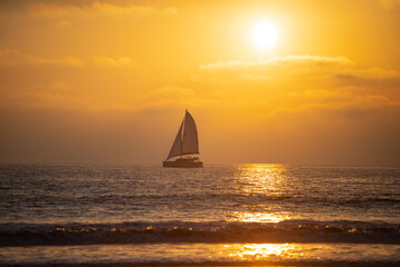Fototapeta na wymiar Sailboat at sea. Seascape golden sunrise over the sea. Nature landscape. Beautiful orange and yellow color on ocean sunset. Seascape with gold sky and clouds.