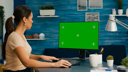 Caucasian woman working on powerful computer with mock up green screen chroma key sitting on desk....