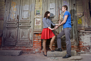 A guy and a girl hold hands on the threshold of an old house. - 435969554