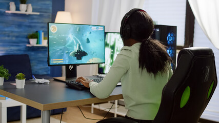 Pro african cyber woman talking with players into headphones and winning video games competition. Professional gamer streaming online videogames with new graphics on powerful computer from gaming room © DC Studio