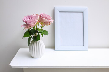 One pale purple rose in a white fluted vase and picture frame with space for text on the table