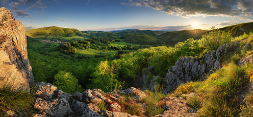 Fototapeta na wymiar Green spring mountain landscape with sun and rocks - panorama