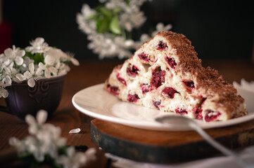 Homemade cake with cherries and cream on a wooden table.