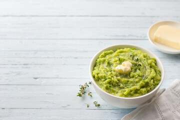 Delicate mashed potatoes with green peas, flavored with butter, spices and thyme on a light blue background. delicious homemade food	