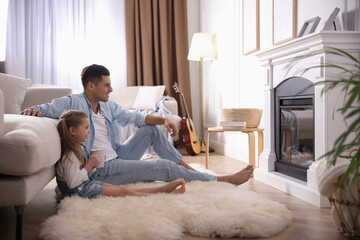 Happy man with his daughter resting near fireplace at home