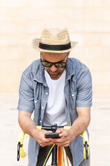 Hispanic man checking his phone on a vintage bicycle. Social media and digital addiction concept.