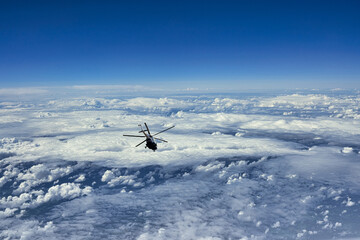Flying helicopter on the background of clouds and blue sky