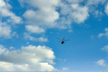 Fototapeta na wymiar Flying helicopter on the background of clouds and blue sky
