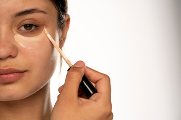  woman applies concealer under her eye