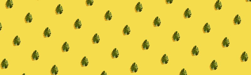 pattern made with fresh exotic palm leaf on yellow background. summer jungle minimal flat lay pattern