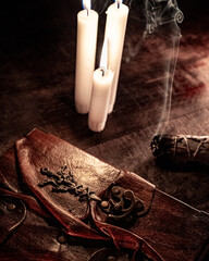 Old antique book with candle and burning smoky incense in vintage style on wooden table. Mystical concept.