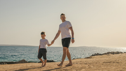 Father and  son  spending time together sea vacation. Young man, little boy walking beach Fathers day. Family with one child. Happy childhood with daddy.