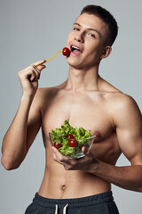 funny sports guy with a naked torso eating vegetable salad energy healthy food