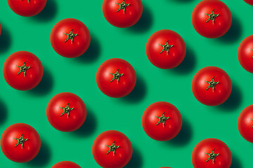 Pattern of fresh and ripe tomatoes isolated on a vibrant green background. Creative minimal food concept. Juicy and organic vegetables composition. Flat lay, top view.