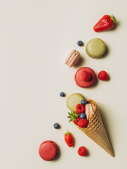 Ice cream cone filled with macaroons, raspberries, blueberries, and strawberries on pastel beige background. Creative food concept. Summer healthy dessert idea. Flat lay, top view.