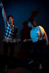 A guy in a plaid shirt and a girl with a dust brush against a dark background