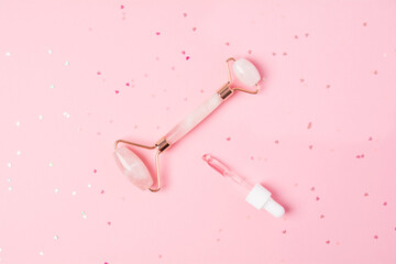 Roller and beauty product on a pink background with sparkles in the shape of hearts. Dropper with serum, oil or other cosmetic product