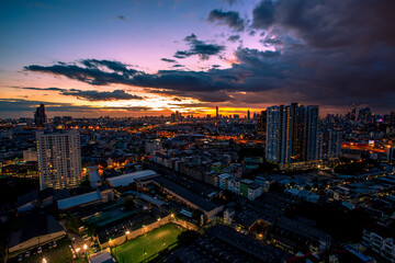 Obraz premium The high angle background of the city view with the secret light of the evening, blurring of night lights, showing the distribution of condominiums, dense homes in the capital community