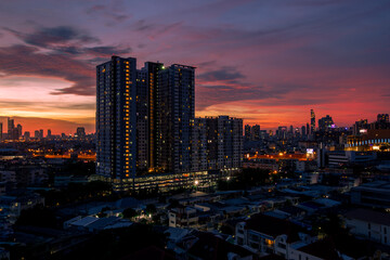 Obraz premium The high angle background of the city view with the secret light of the evening, blurring of night lights, showing the distribution of condominiums, dense homes in the capital community